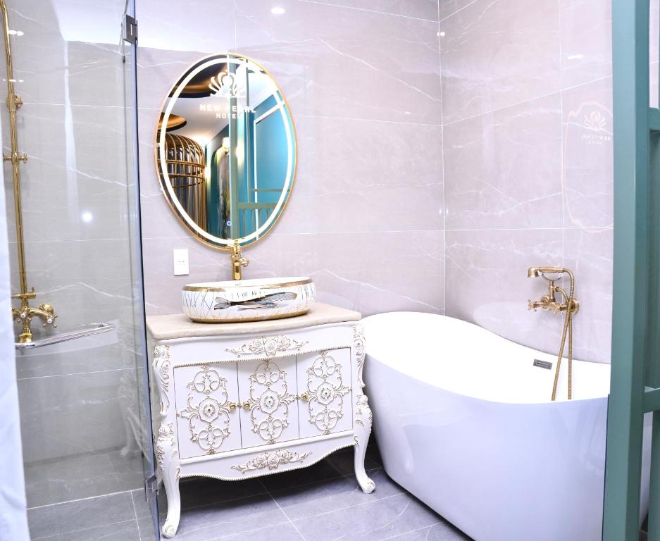 a bathroom with a tub and a sink and a mirror at New Pearl Hotel in Ho Chi Minh City