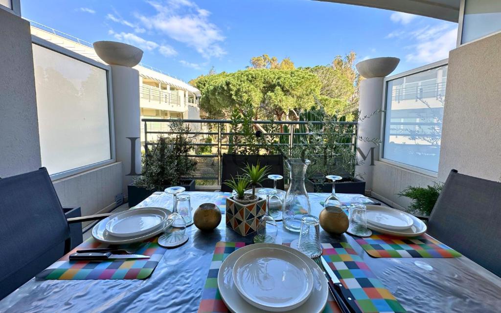 une table avec des assiettes et des verres sur un balcon dans l'établissement Studio Bis Rivages 100m de la plage, lumineux, à Calvi