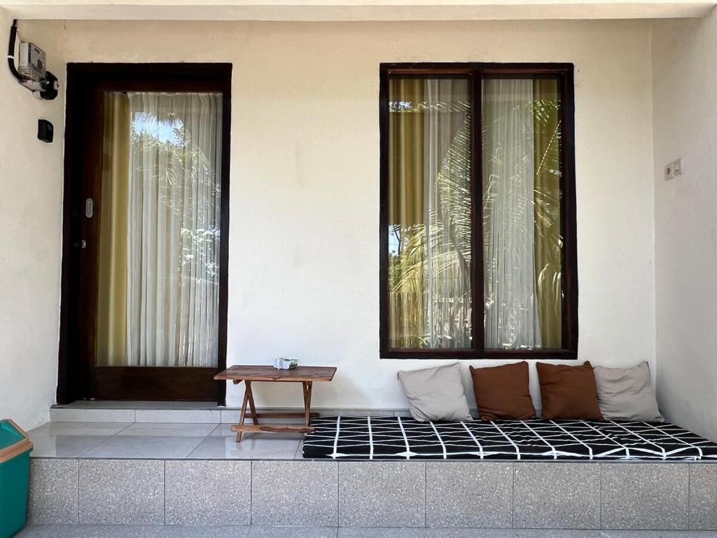 un sofá sentado frente a dos ventanas en B-local mong guest house, en Kuta Lombok