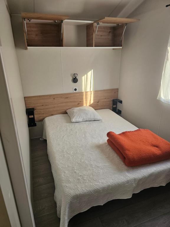 Un dormitorio con una cama con una manta naranja. en Mobilehome cosy, en Biscarrosse