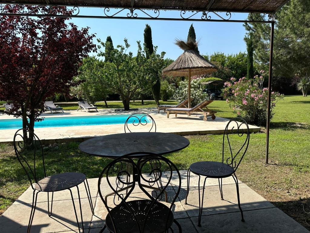 - une table et des chaises dans une cour avec une piscine dans l'établissement La maison à couleur - Mas provençal avec piscine, à Châteaurenard