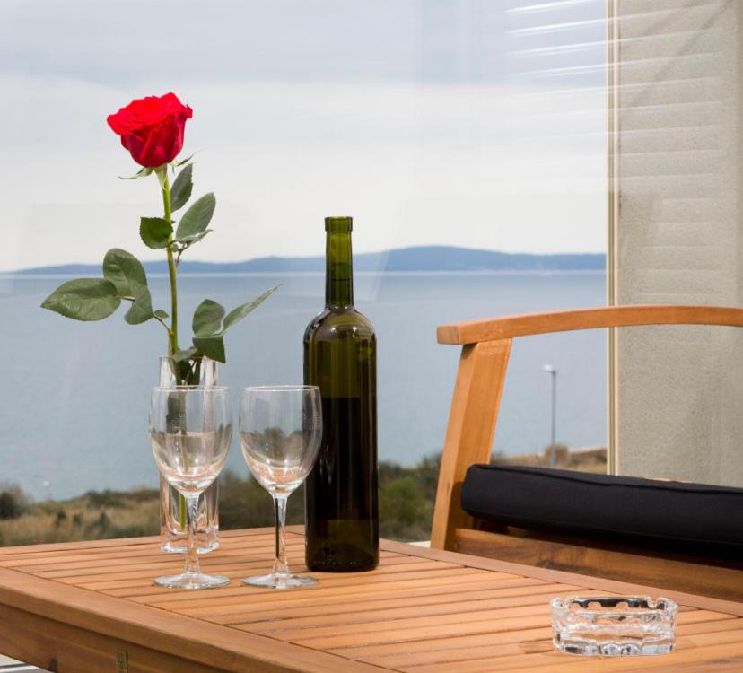 eine Flasche Wein und zwei Gläser auf dem Tisch mit einer Rose in der Unterkunft Apartment Ema in Split
