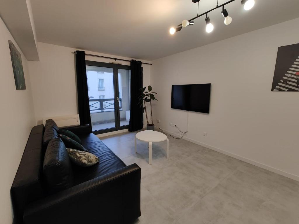 un salon avec un canapé noir et une télévision dans l'établissement Confortable 54m2 NEW Paris Nation Gare de Lyon, à Paris