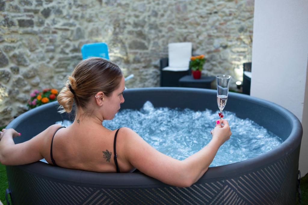 a woman in a hot tub with a glass of water at Lo Scacciapensieri in Montecastrilli