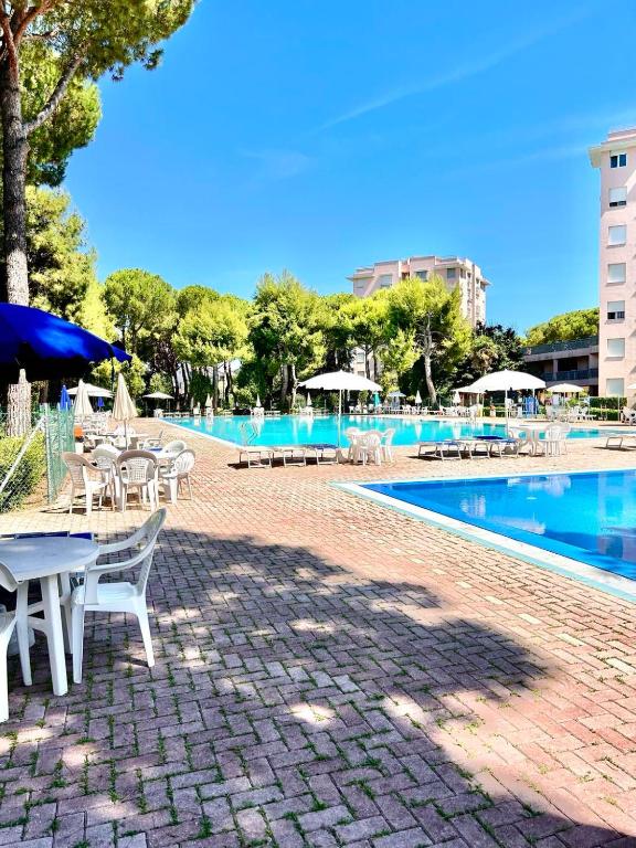 a swimming pool with tables and umbrellas next to at Trilo Stefano in residence con piscina, vicino al mare in Marcelli
