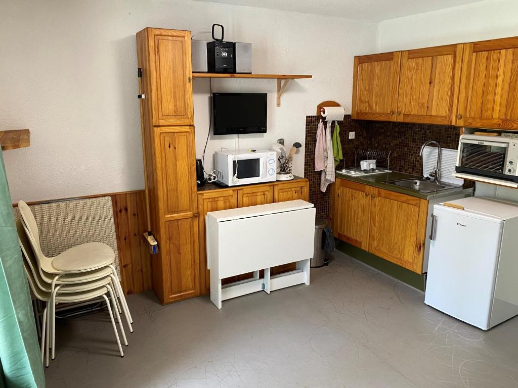 - une cuisine avec des placards en bois et un four micro-ondes blanc dans l'établissement Appartment de Montagne Bonascre Ax 3 Domains, à Ax-les-Thermes