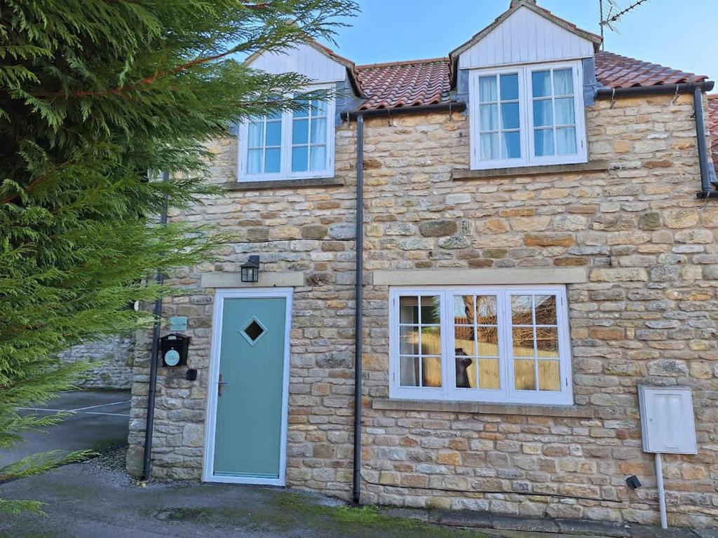 a stone house with a blue door and windows at Dandelion Cottage - a gorgeous family cottage in Snainton