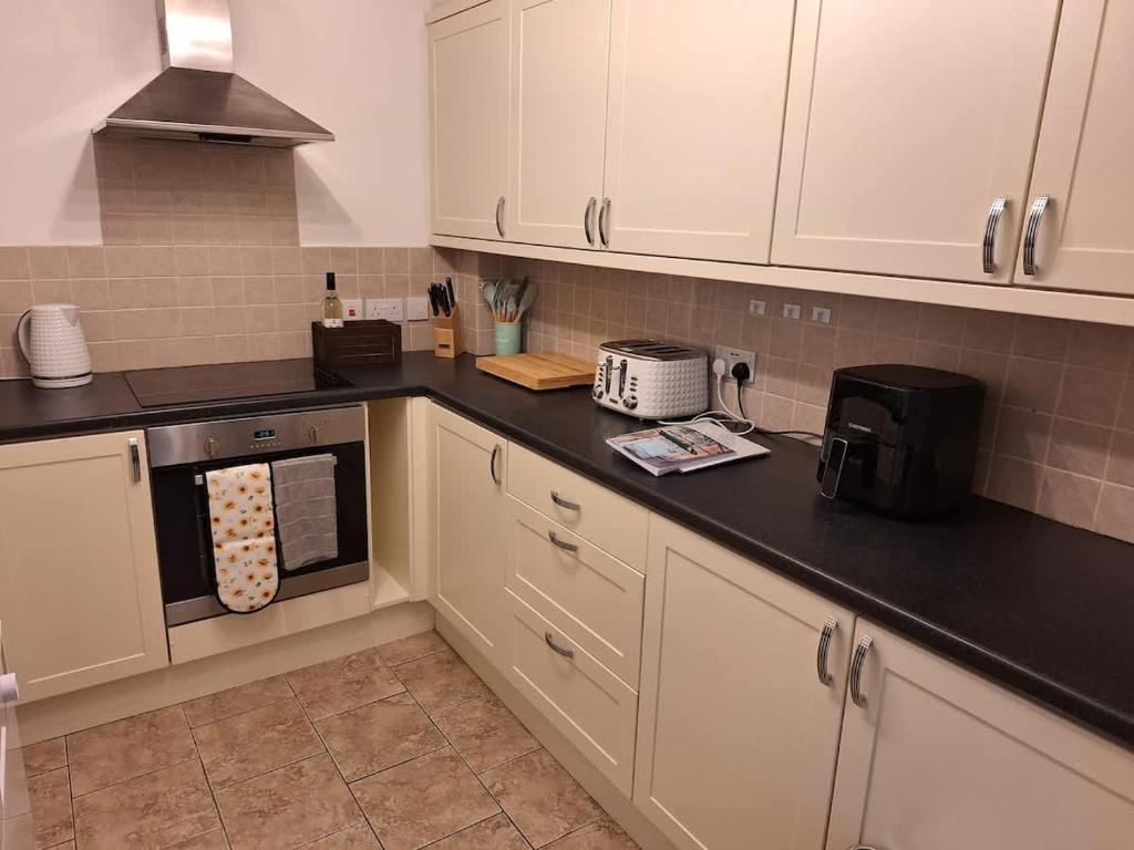 a kitchen with white cabinets and a black counter top at Sunflower Cottage - a charming family cottage in Snainton