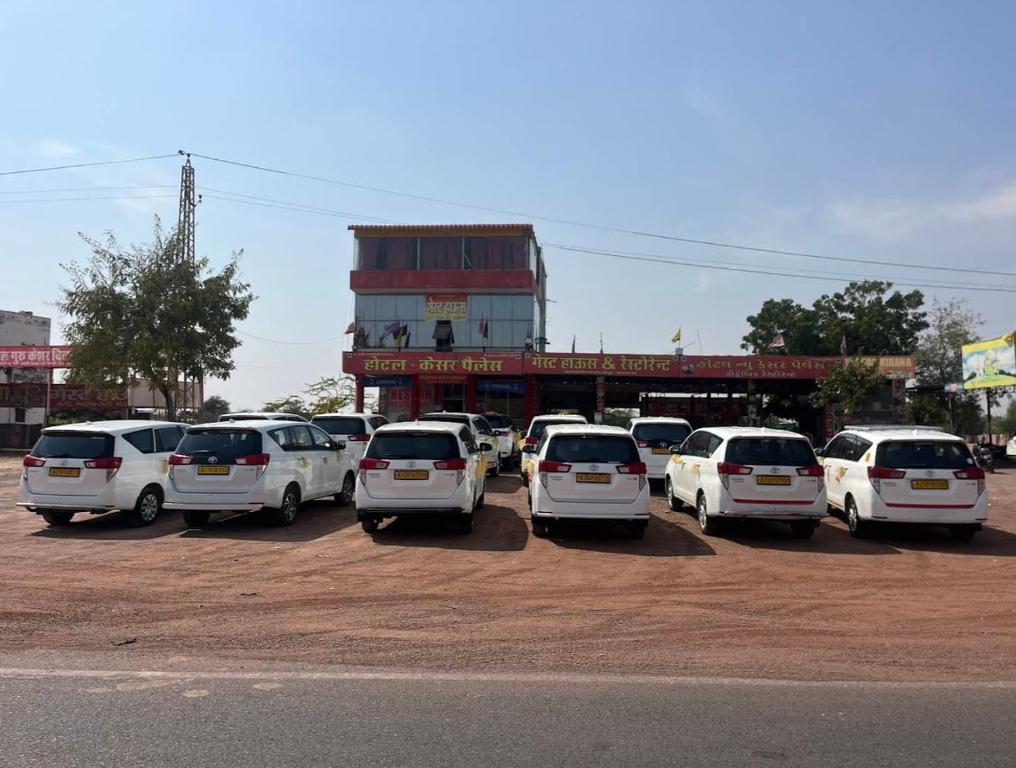 a group of white cars parked in a parking lot at Hotel New Kesar Palace in Agolai