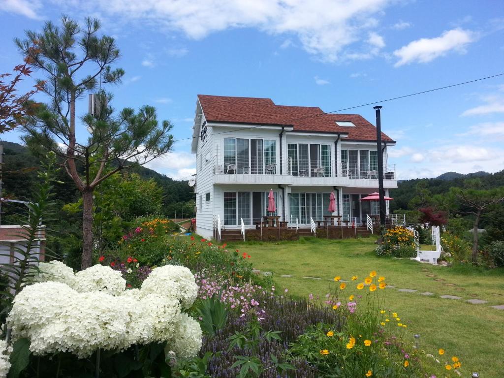 a white house with flowers in front of it at Walking Sky Pension in Gapyeong