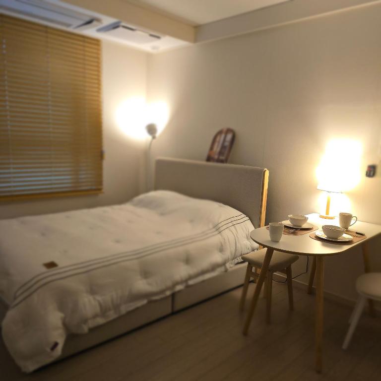 a bedroom with a bed and a table with two cups on it at 원 스테이 광명역 in Gwangmyeong