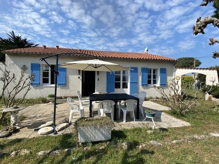 une maison avec une table, des chaises et un parasol dans l'établissement Maison 5 pièces 8 couchages Saint Georges d'Oléron SGO000-115, à Saint-Georges-dʼOléron