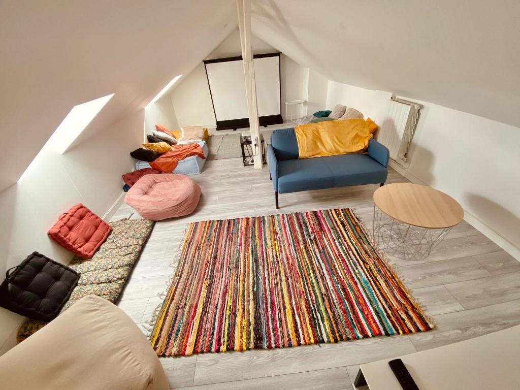 Cette chambre mansardée comprend un canapé et un tapis. dans l'établissement Belle appartement 4 chambres, à Reims