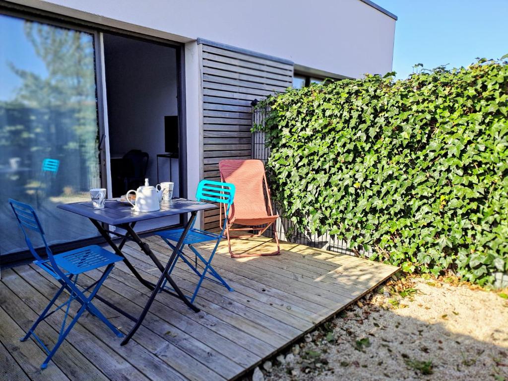 une table et des chaises assises sur une terrasse en bois dans l'établissement Cordouan, à Saint-Palais-sur-Mer