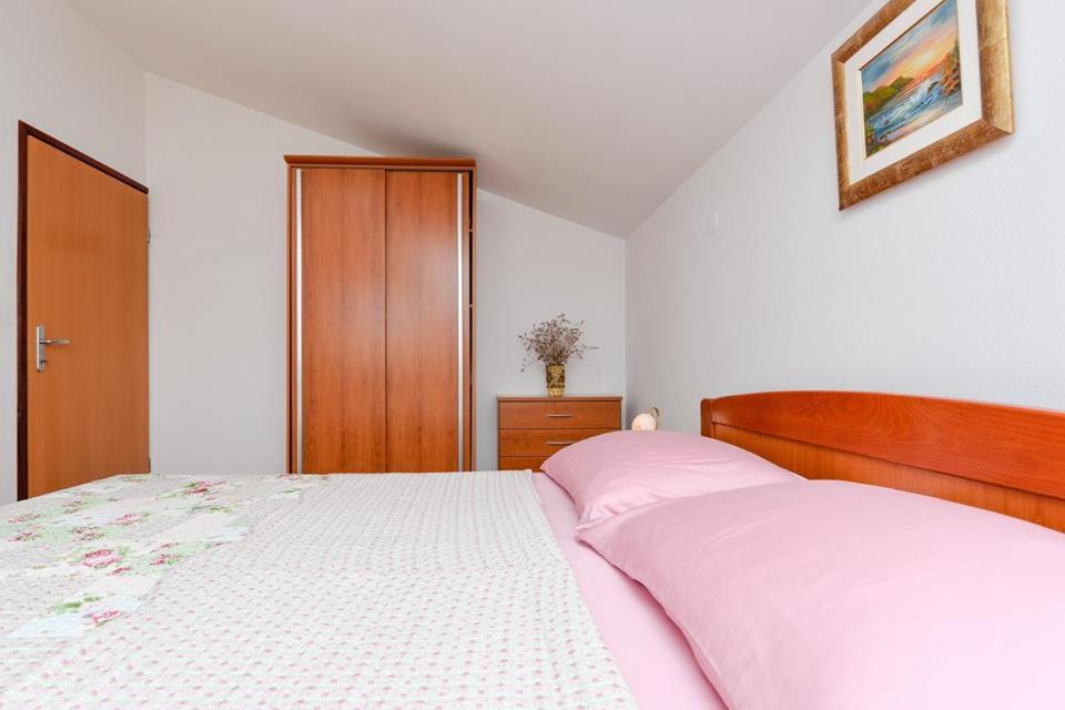 Schlafzimmer mit einem weißen Bett mit einem Kopfteil aus Holz in der Unterkunft Apartments Manuela in Zadar