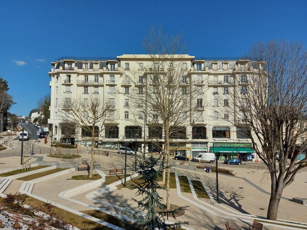 un grand bâtiment blanc avec des arbres devant lui dans l'établissement Studio résidence Grand Hôtel, à Châtel-Guyon
