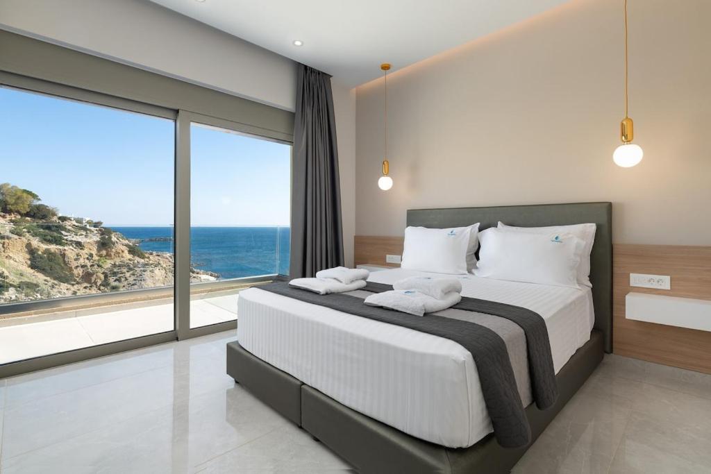 a bedroom with a large bed with a view of the ocean at Aquamarine Luxury Suites in Archangelos