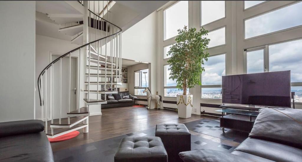 un grand salon avec un escalier et une grande télévision dans l'établissement Paris en hauteur, à Paris