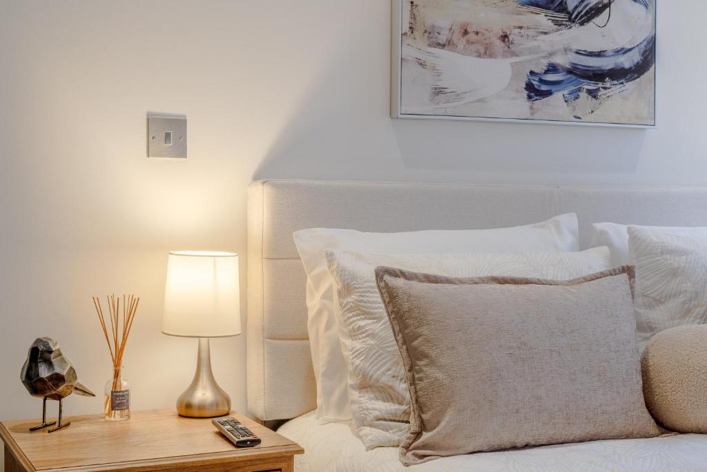 a bedroom with a white bed with a table with a lamp at Arliss Suite in Watford