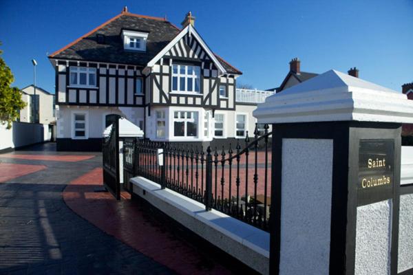 una gran casa en blanco y negro con una valla en St Columbs House en Buncrana