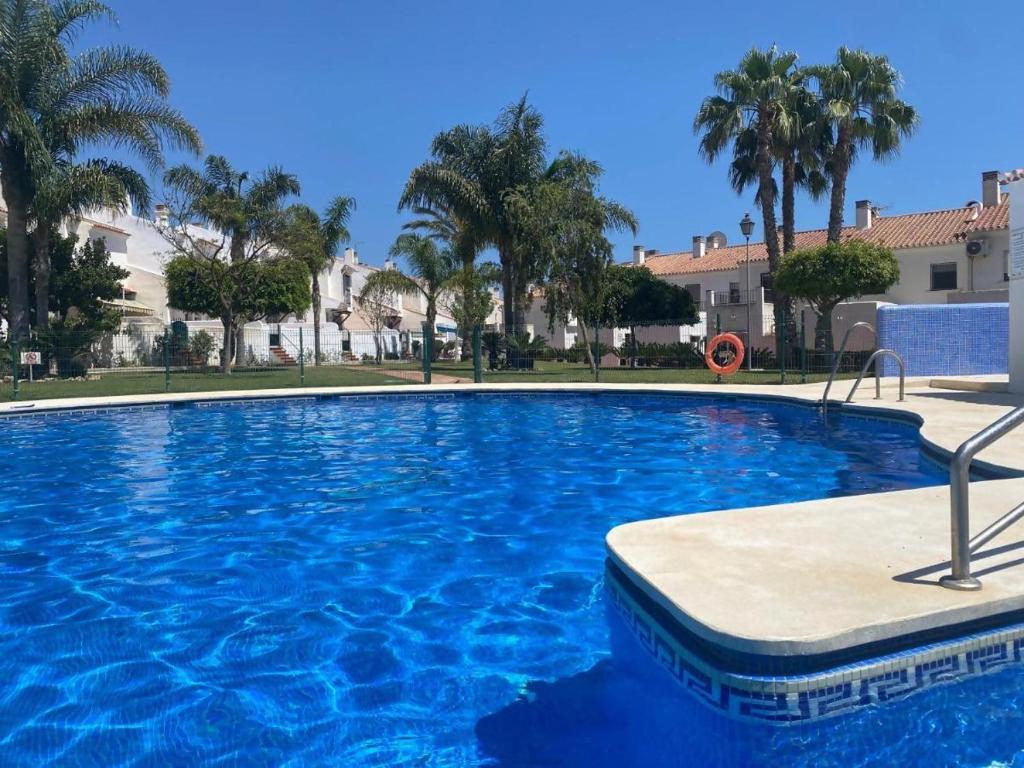 a large blue swimming pool with palm trees and buildings at Casa Segovia By Solymar Holiday in Caleta De Velez