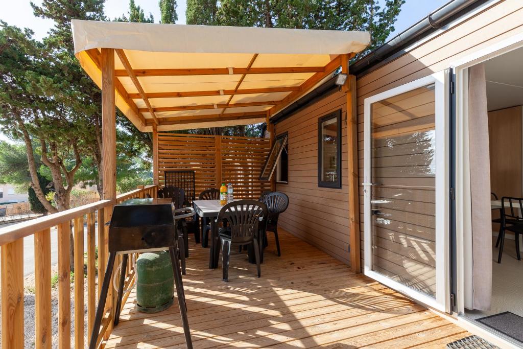 un patio avec une table et des chaises sur une terrasse dans l'établissement Mobil home tout équipé, à Carry-le-Rouet