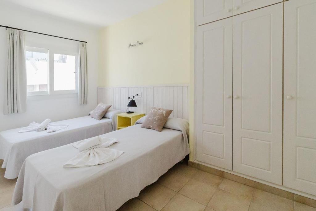 Un dormitorio con dos camas y una ventana. en Apartamentos Timon - Emar Hotels, en Es Pujols