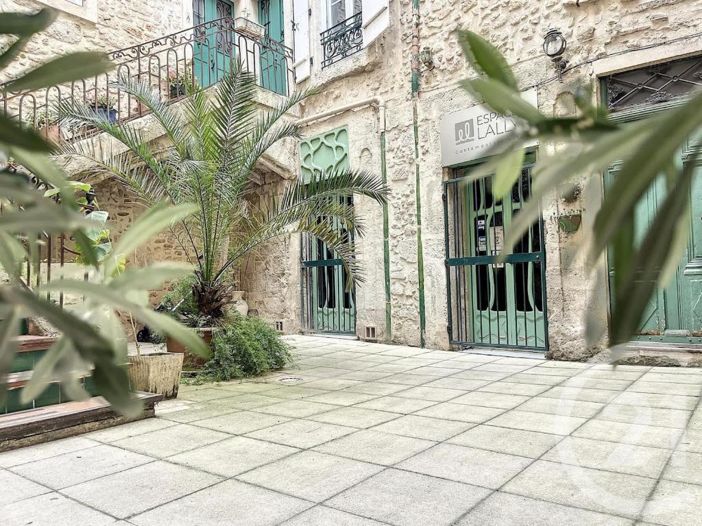 Una calle vacía con un edificio con puertas verdes. en Art&Heart - Centre historique, en Béziers