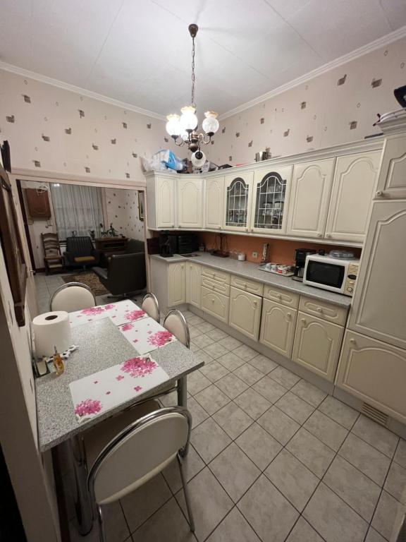 une cuisine avec des armoires blanches et une table avec des chaises dans l'établissement Maison 3 chambres, à Roubaix