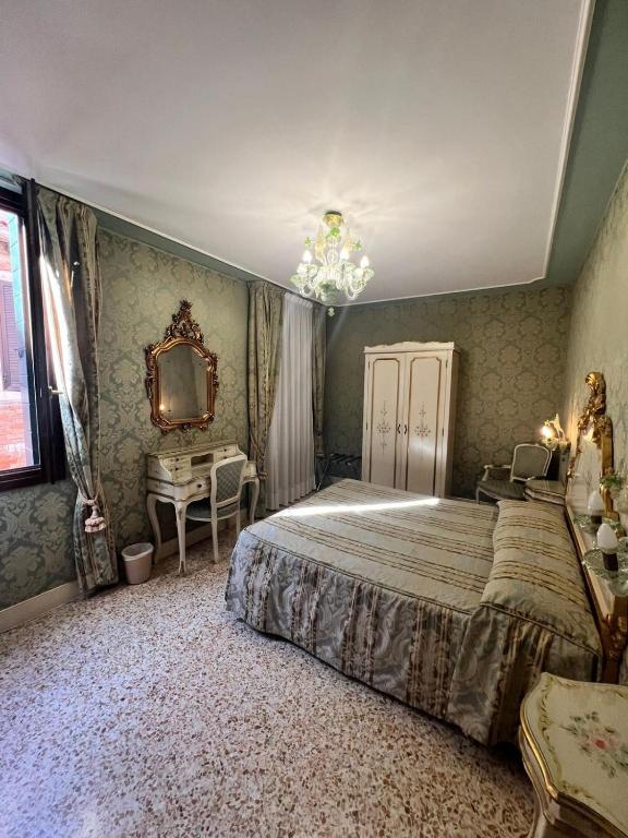 a bedroom with a bed and a desk and a mirror at Hotel Ca' Dogaressa in Venice