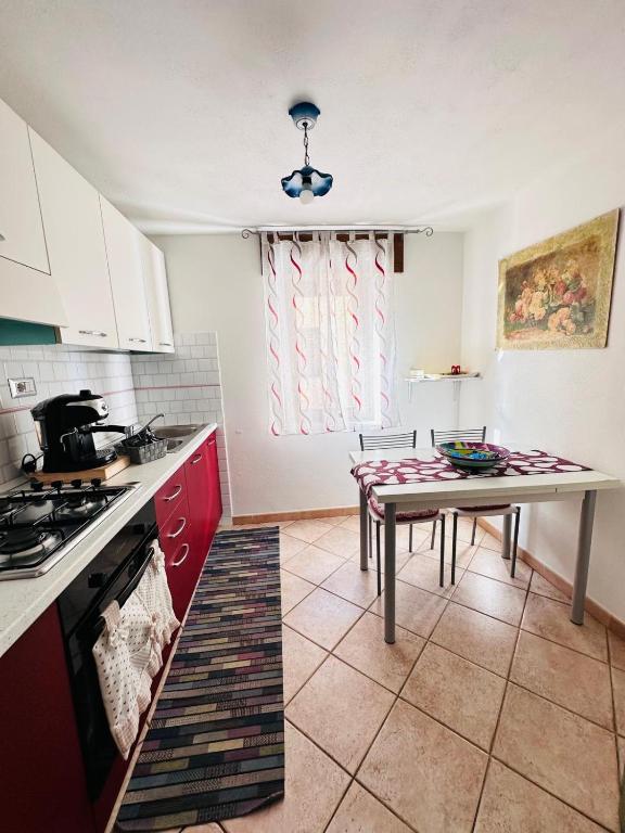 kuchnia z czerwonymi szafkami i stołem w obiekcie Appartamento 5 Vista Panoramica w mieście Cala Gonone