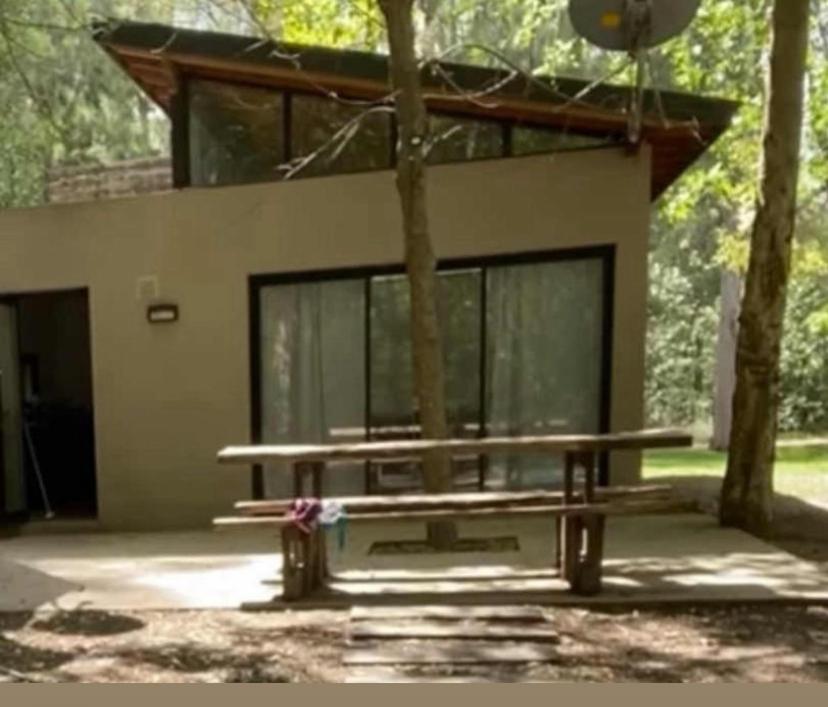 a house with a bench in front of it at Descanso en el Bosque in Brandsen