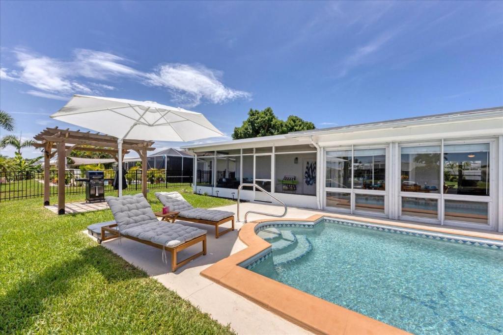 a pool with two chairs and an umbrella next to a house at MAD510 Punta Gorda Isles in Punta Gorda