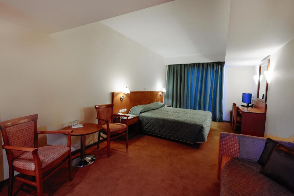une chambre d'hôtel avec un lit, une table et des chaises dans l'établissement Athens Mirabello, à Athènes