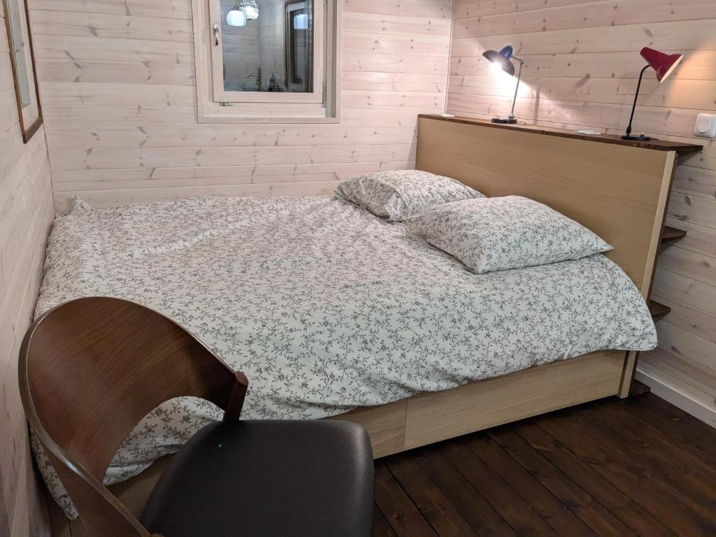 a bedroom with a bed with a chair and a lamp at Roulotte avec terrasse à Montreuil in Montreuil