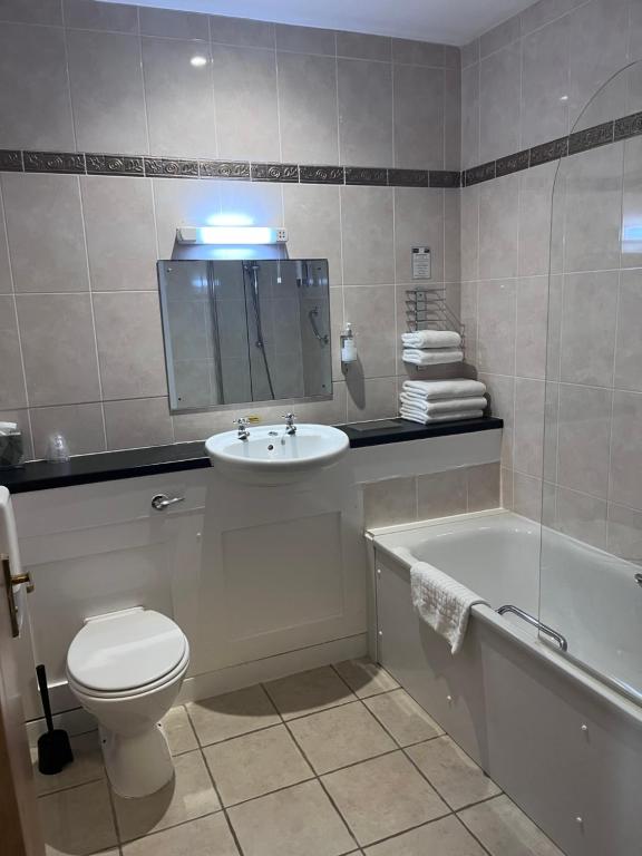 a bathroom with a toilet and a sink and a tub at Inn On The Coast in Portrush