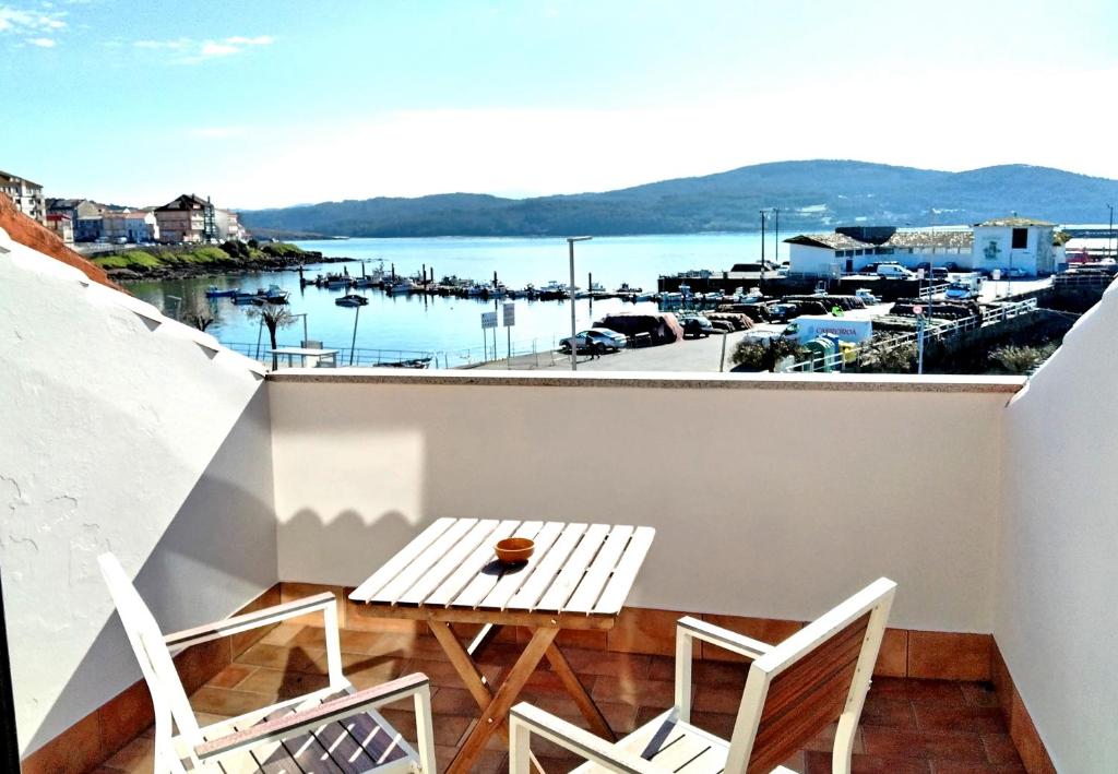 a balcony with a table and chairs and a view of a harbor at Hotel Puerto Arnela in Camariñas
