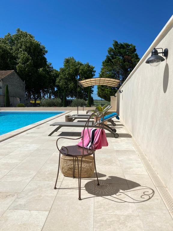 un patio avec des chaises à côté d'une piscine dans l'établissement Tilleul - Laurier gite rural du Domaine de Laforest, à Fontvieille