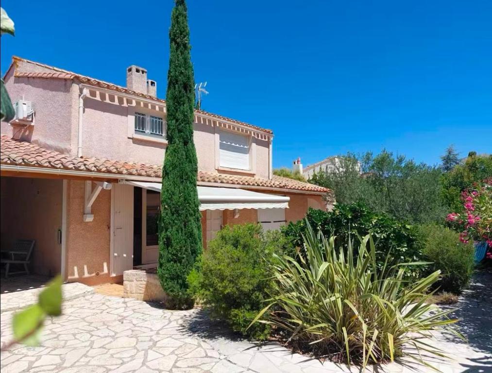 une maison avec un grand arbre dans une cour dans l'établissement Maison Familia - 8 pers - Histoire de Clés, au Cap d'Agde