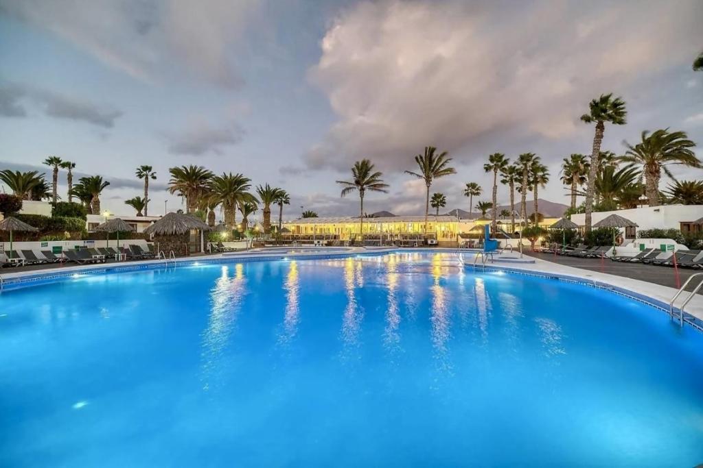 una gran piscina azul con palmeras en el fondo en Las Brisas Villa 106, en Playa Blanca