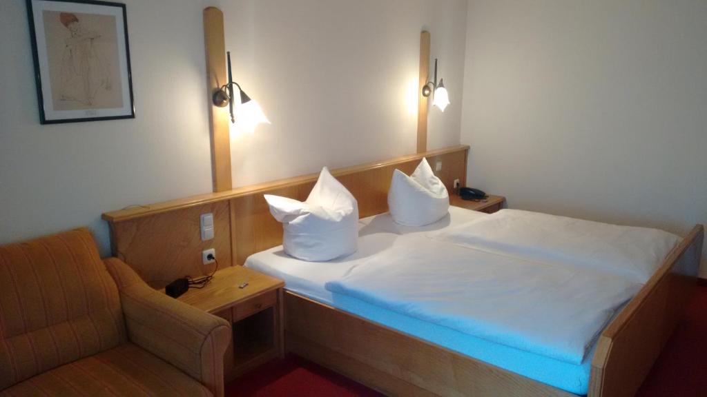 1 dormitorio con 1 cama con 2 almohadas y 1 silla en Hotel Pfaubräu, en Trostberg an der Alz
