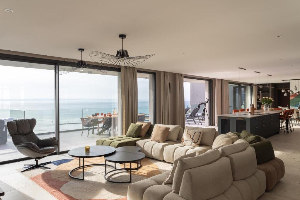 un salon avec un grand canapé et des chaises dans l'établissement L'Odyssée du Val - Vue mer, à Pléneuf-Val-André