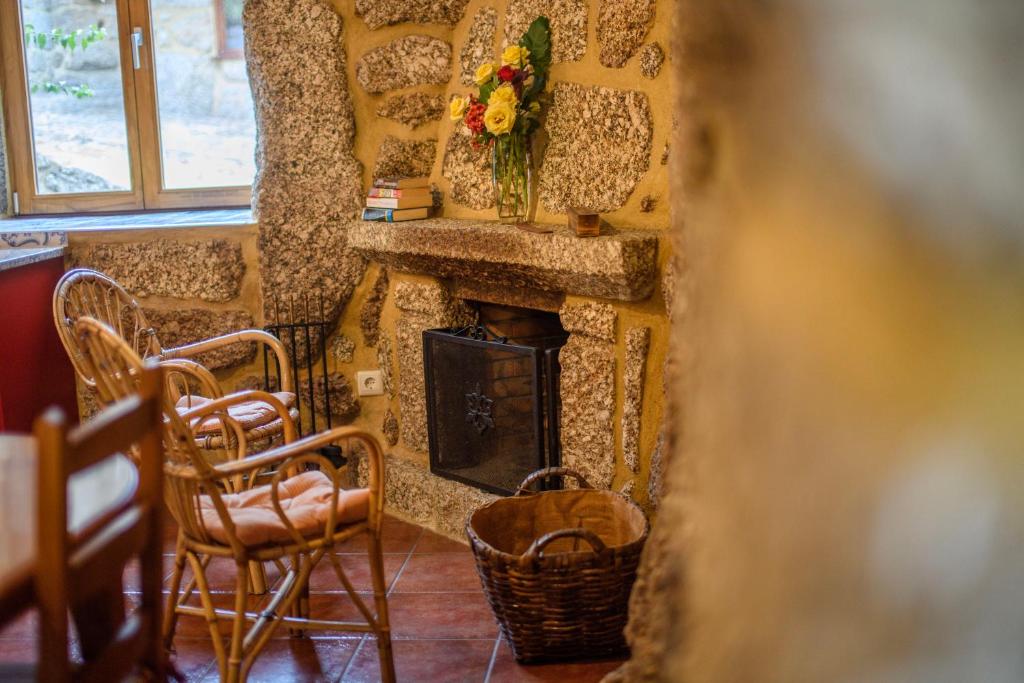 una camera con una parete in pietra, sedie e un camino di Gerês Country Stays - Sequeiro a Rio Caldo
