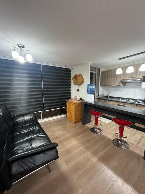 a living room with a black leather couch and a kitchen at Comfort y Estilo in Constitución