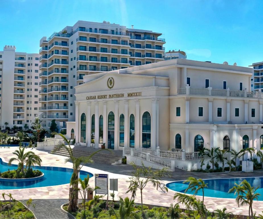 Un gran edificio blanco con palmeras en frente de un edificio. en Caesar Resort 2 Bedroom, Pool View, Close to the Beach, en Trikomo