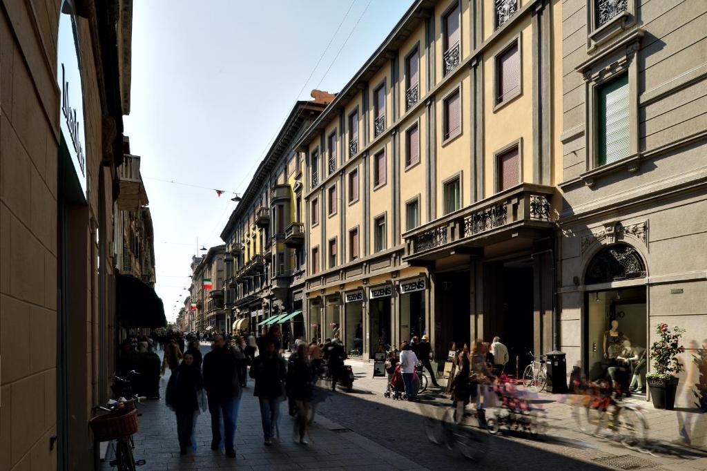un gruppo di persone che camminano per una strada con edifici di My House Apartments a Cremona
