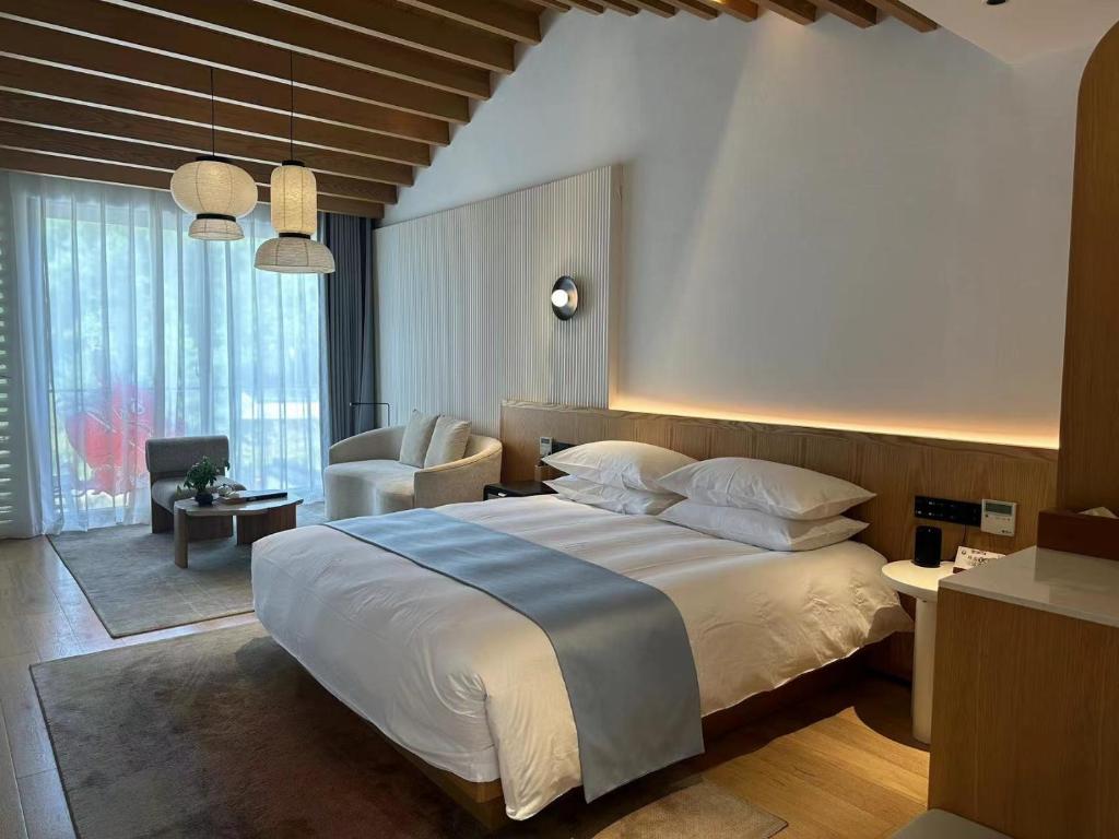 Un dormitorio con una cama grande y una sala de estar en 乌镇乌外坞酒店, en Tongxiang