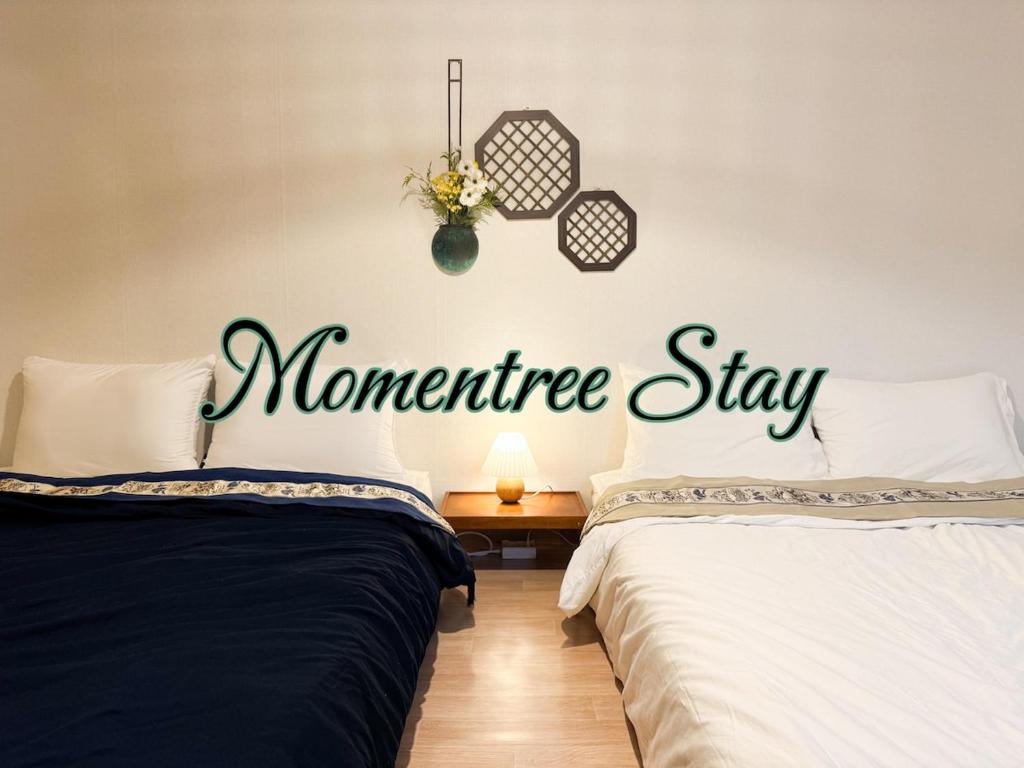 2 camas en una habitación con un cartel para una estancia hipotecaria en Momentree Stay, en Seúl