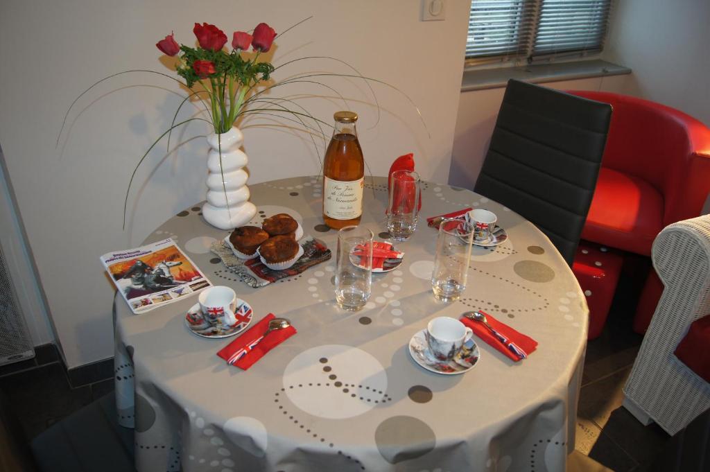 - une table avec une bouteille de vin et un vase de fleurs dans l'établissement La Citadine, à Bayeux