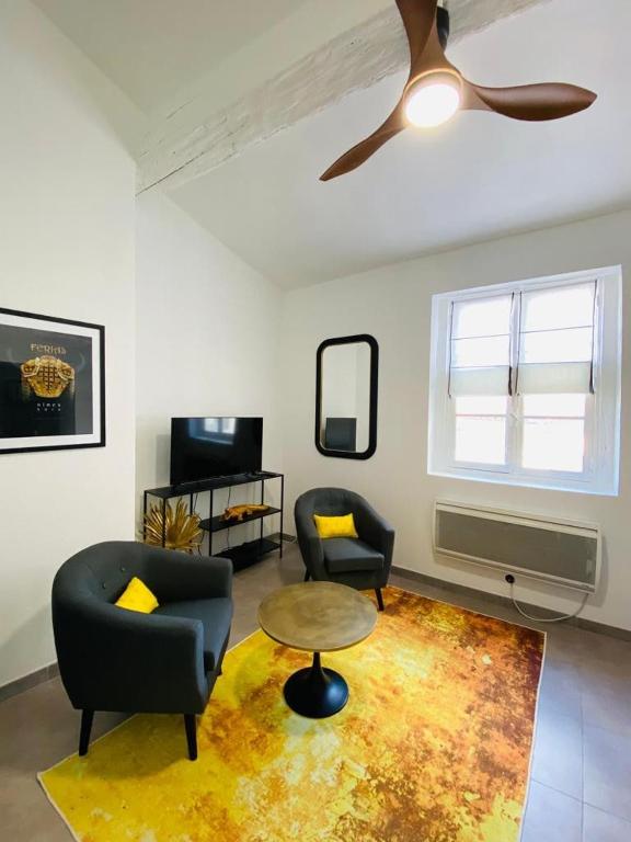 - un salon avec deux chaises et un ventilateur de plafond dans l'établissement Appartement centre historique, à Nîmes